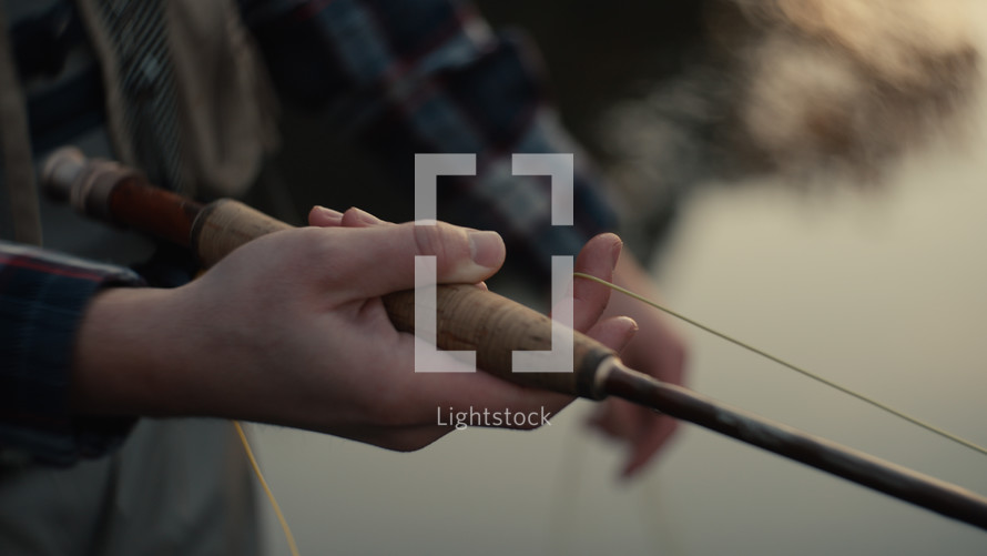 Young fly fisherman casting on a foggy river at sunrise