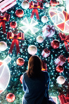 a woman looking at a Christmas light display 