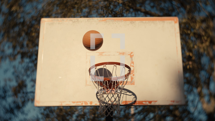 Close up of a basketball being shot on an outdoor basketball court on a sunny day