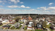 Aerial view of a church in a small town with beautiful blue skies and clouds.