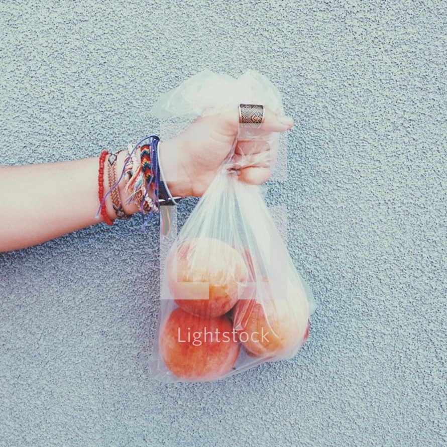 a hand holding a bag of peaches 
