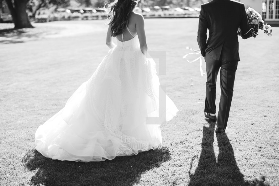 bride and groom walking across a lawn 