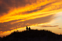Silhouette of two people on a hill viewing a sunset