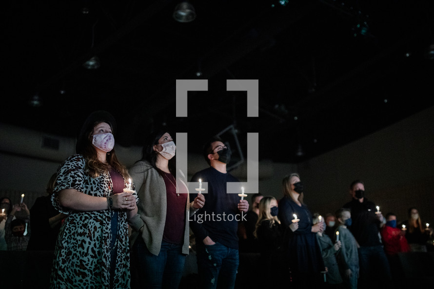 parishioners holding candles during a worship service 