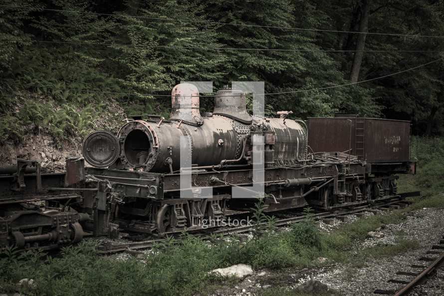 Old abandoned locomotive on train tracks in the woods