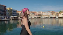 Woman tourist enjoying Bay Of Chania At Sunny Summer Day In Crete, Greece. Smiling and opening arms
