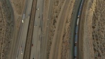 aerial view over a train on the tracks and traffic on a highway 