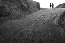 couple holding hands walking down a dirt road