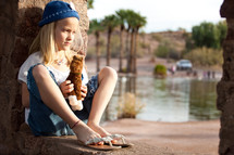 girl child sitting holding a stuffed animal horse