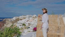 Tourist travel woman in Oia, Santorini, Greece. Young woman on famous landmark destination. Tourist visiting the Greek island.
