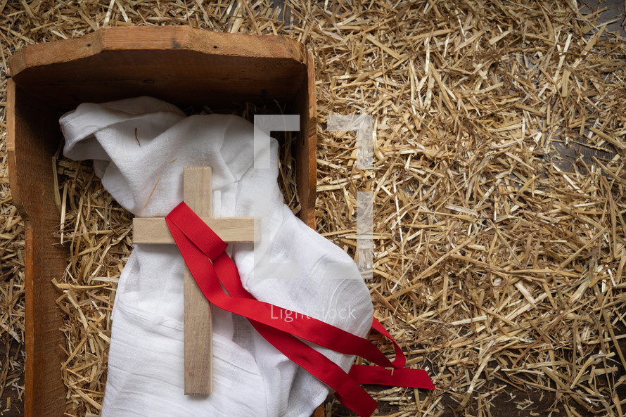 cross with red ribbon in a manger 