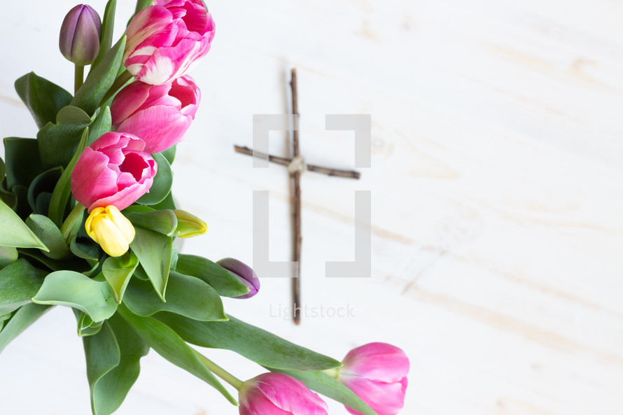 pink and yellow tulips and a cross made of sticks 