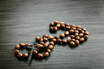 Wood rosary on a dark wood background with copy space