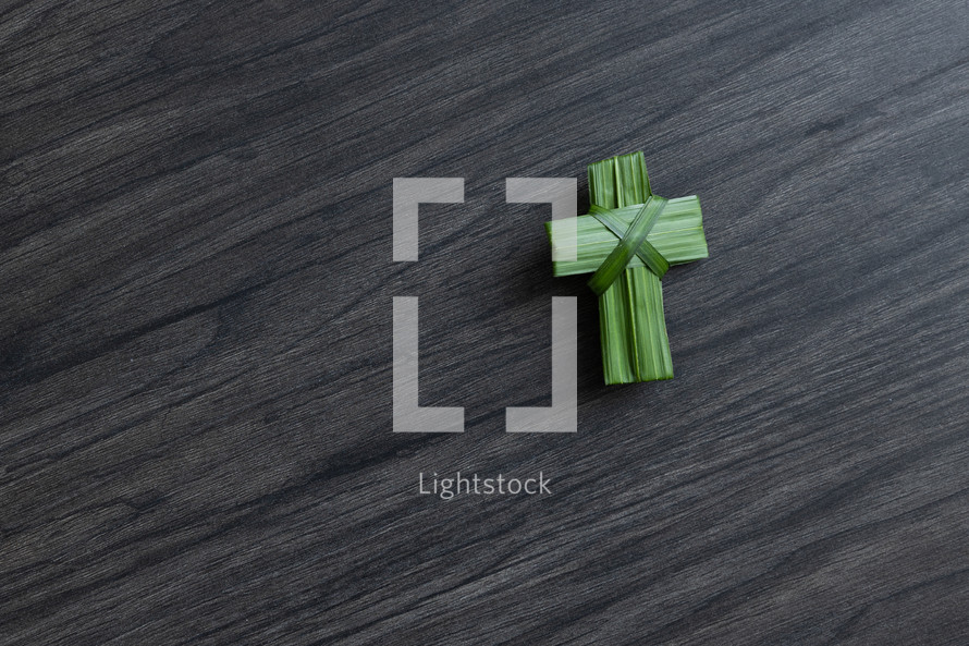 palm frond cross on a gray wood background 