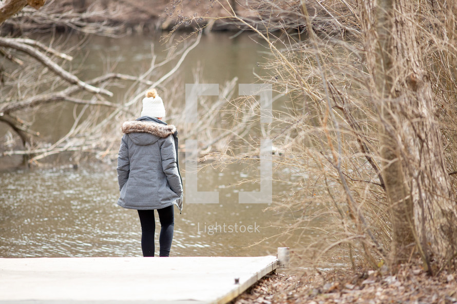 a woman in a coat looking at water 