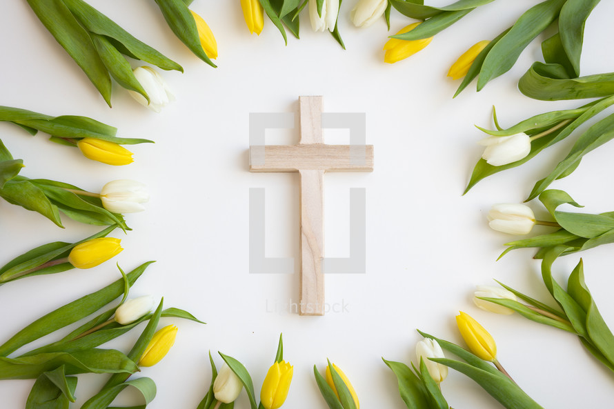 Cross framed by yellow and white tulips on a white background