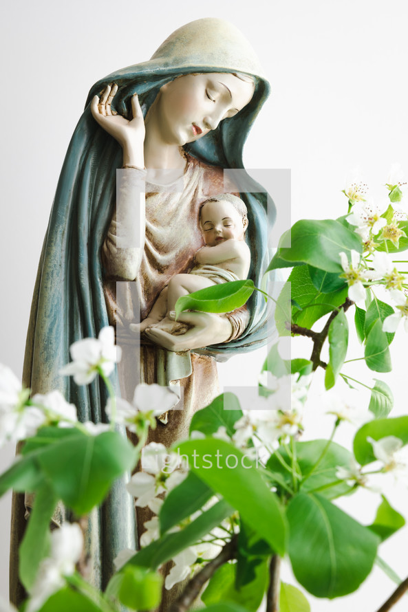 Statue of Mary holding baby Jesus with spring flowers 