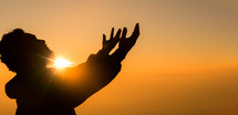 Silhouette of a man praying at sunset