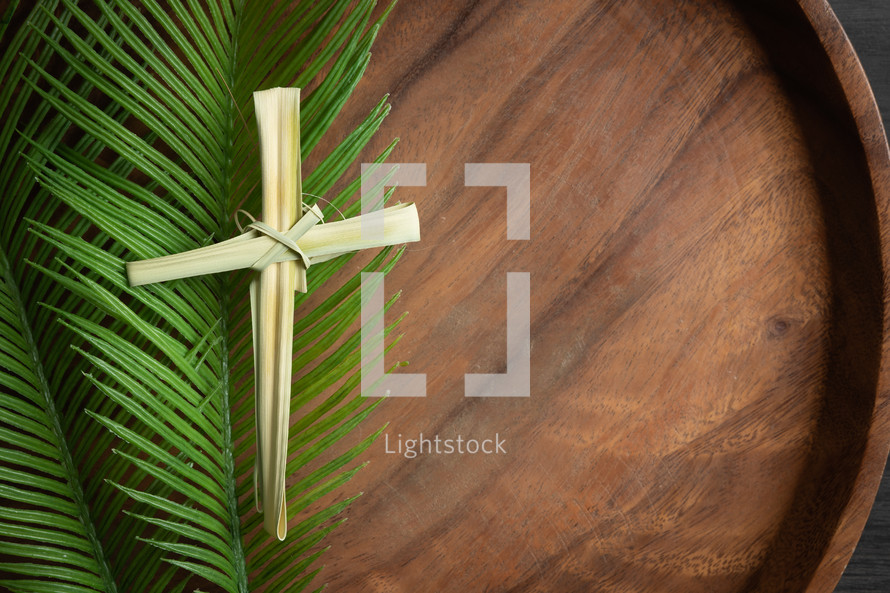 dried palm cross on palms on teak wood