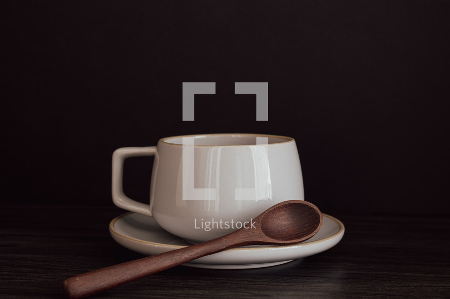 White mug and saucer with wooden spoon