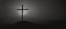 Cross on a hill during a vibrant sunrise - black and white