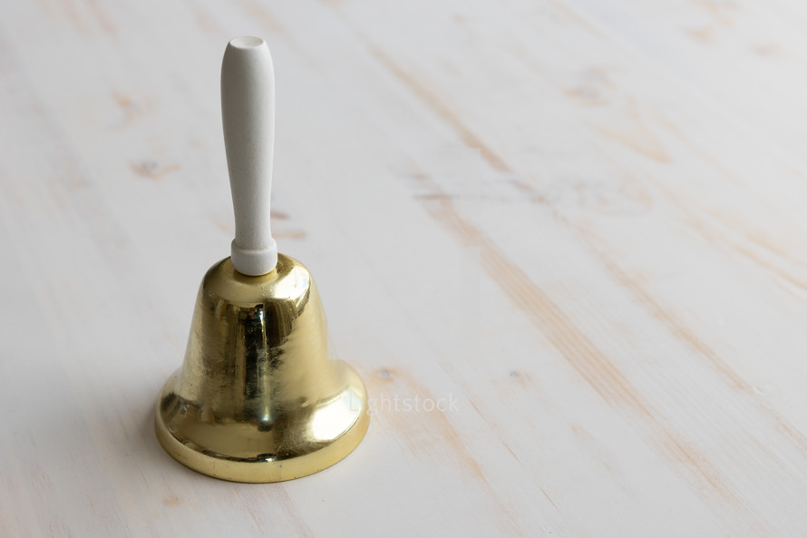 gold and white bell on white wood