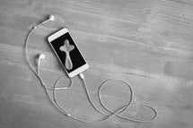 black and white, phone, earbuds and wood cross on wood
