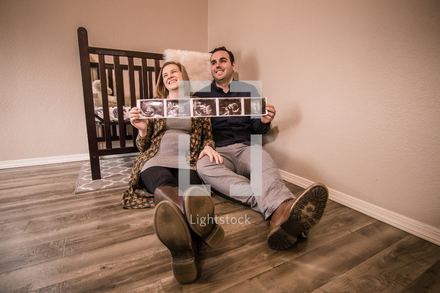 mother and father holding ultrasound pictures 