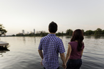 couple holding hands in front of a lake