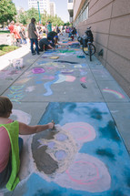 people gathered using sidewalk chalk drawing on a sidewalk 