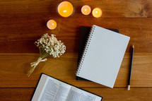 open Bible, journal, and candles on a wood background 