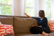 a woman sitting on a couch looking out a window 