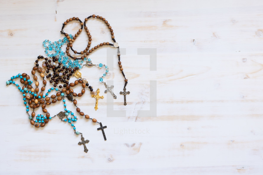 rosaries on a white wood background 