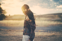 a young woman walking in a field at sunset 