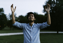 A man with hands raised praising God outdoors 