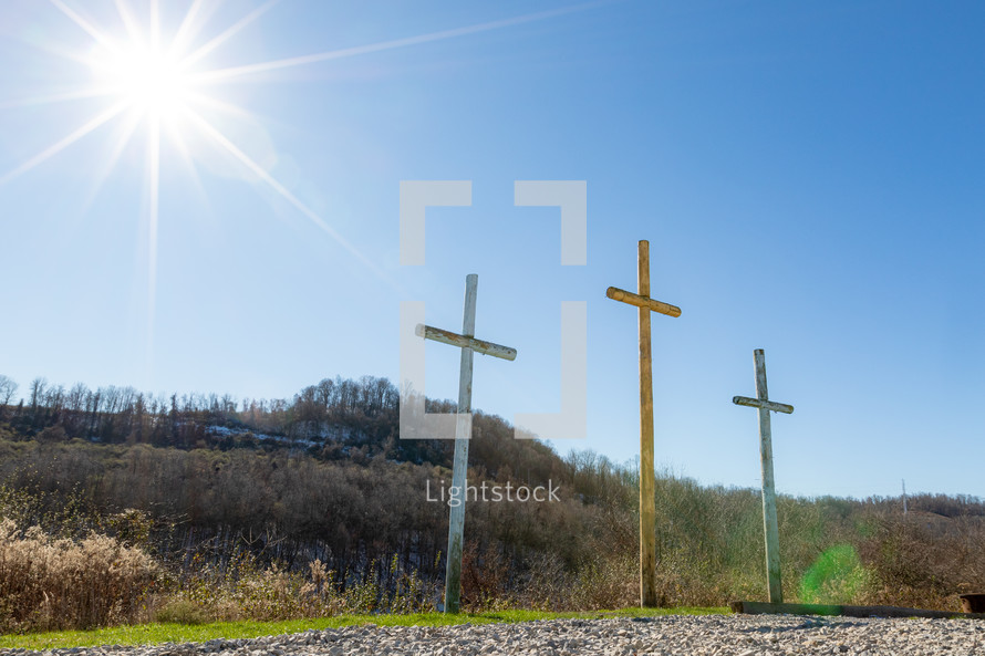 Sunlight on three wooden crosses on hill