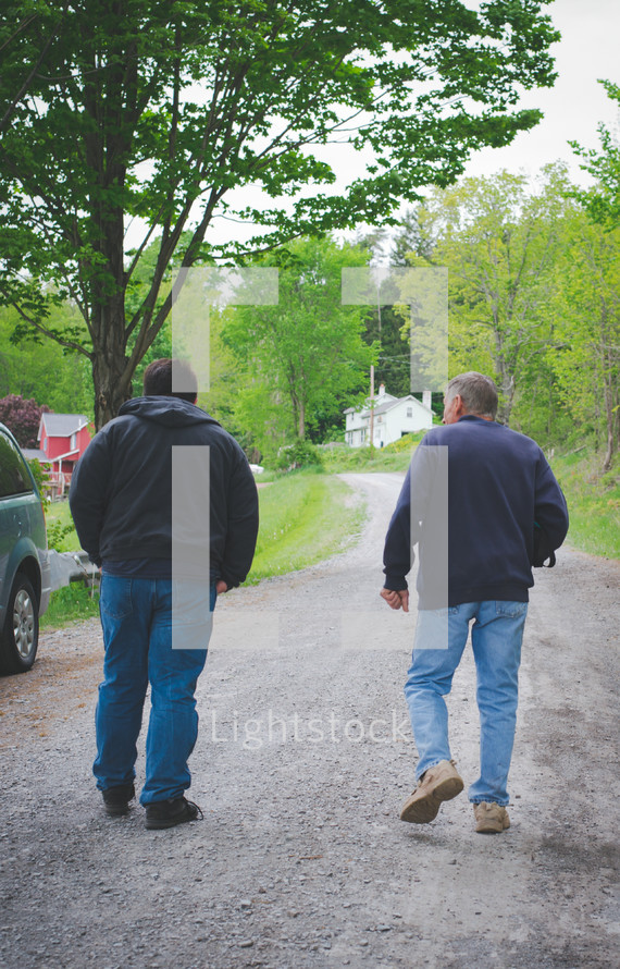 father and son walking down a gravel driveway 