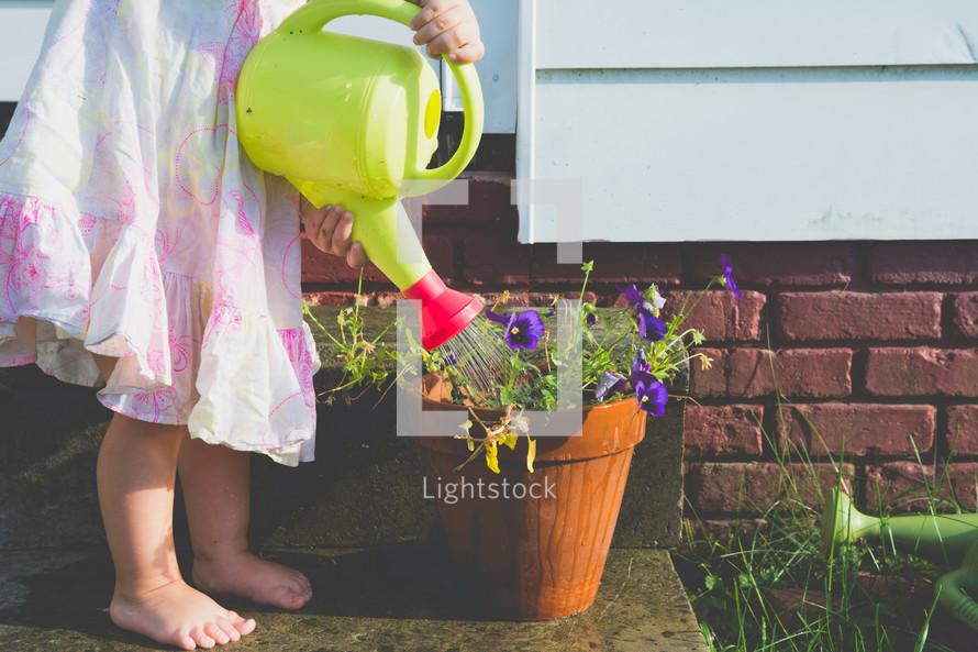 a girl watering a plant with a watering can 