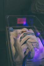 Newborn baby receiving UV treatment for jaundice in a hospital.