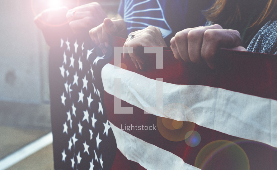 hands holding the edge of an American flag 