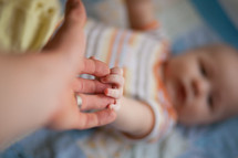 parent and infant holding hands