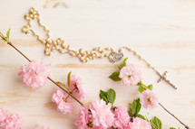 Rosary with pink flowers on a white background