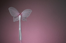 Pink decorative butterfly wand with heart shaped jewel head and ribbons.