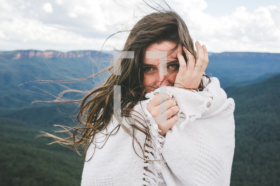woman wrapped in a blanket standing on a mountain top 