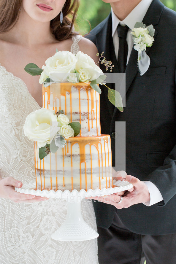 bride and groom holding a wedding cake 
