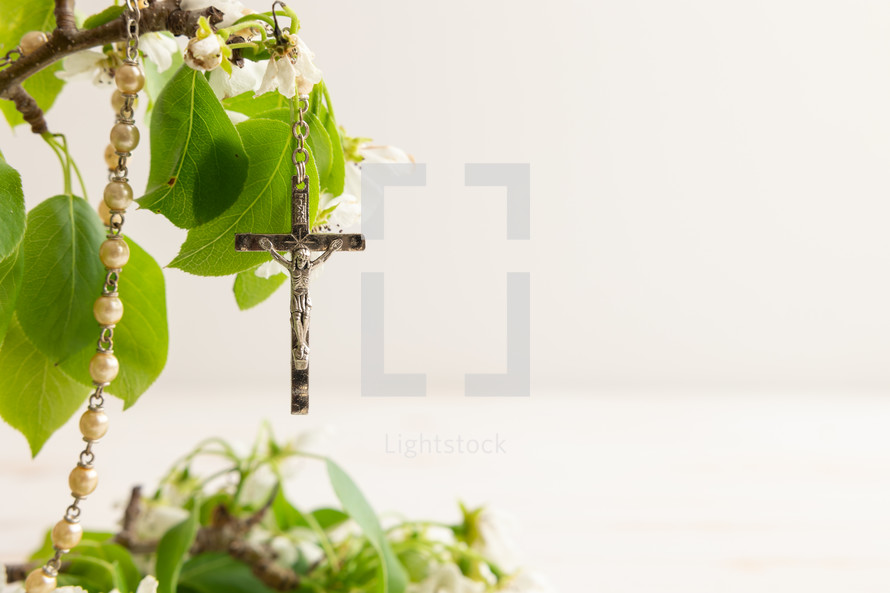 Rosary prayer beads hanging on a branch with spring blossoms