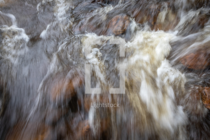 Water rushing over rocks along river rapids 