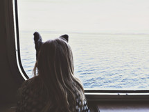 girl looking out a ferry window 