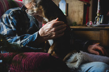 a dog sitting in the lap of an elderly man 