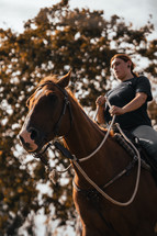 Horse riding woman on a brown stallion, western style saddle horseback rider